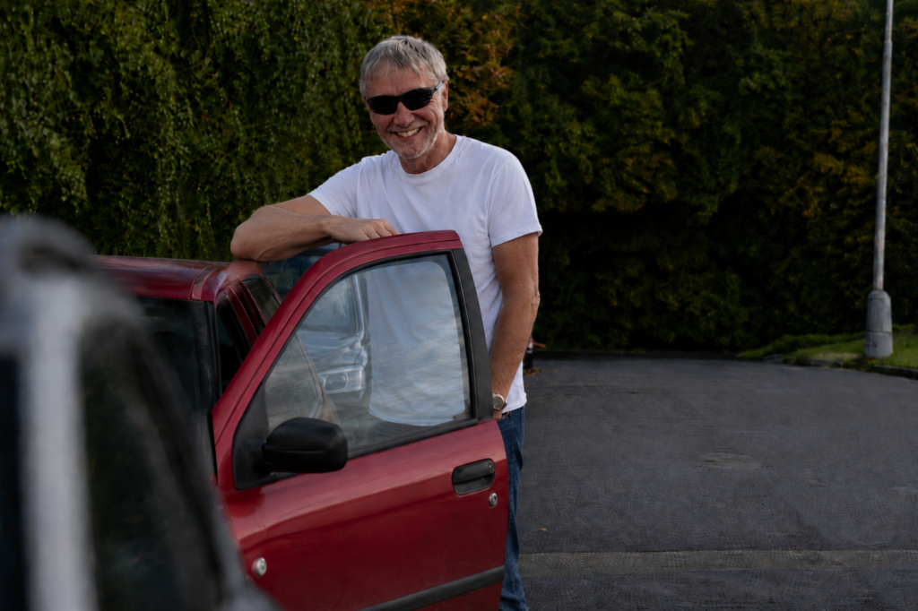 smiling man by red car class five driving lesson day
